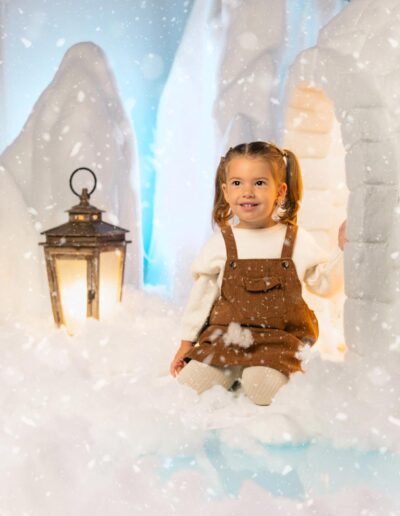 Niña sentada junto al farol y el iglú del decorado navideño
