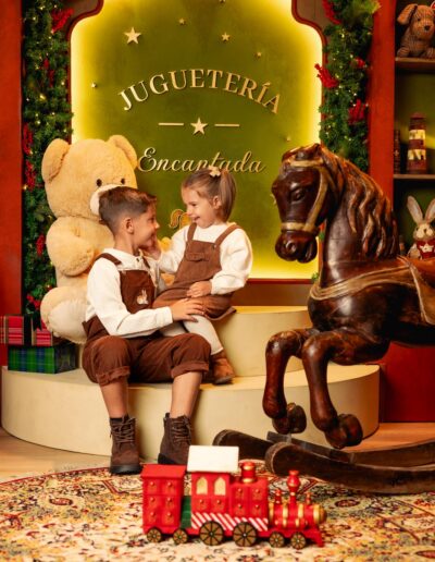 Dos niños posando entre juguetes y regalos navideños
