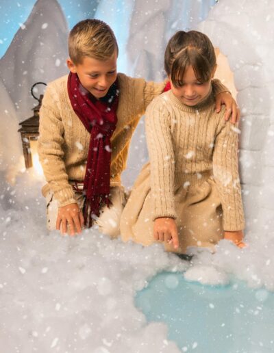 Dos hermanos juntos ante el fondo nevado del decorado navideño