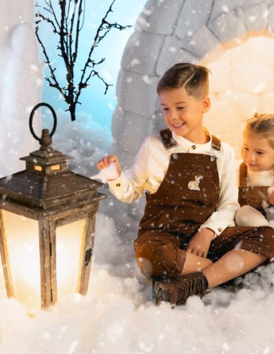 Padre e hija posando junto al iglú del decorado navideño