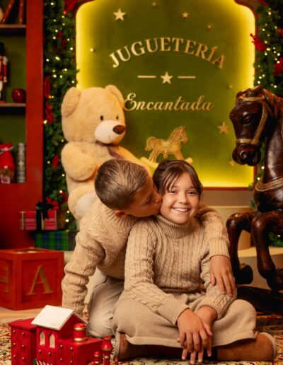 Hermano y hermana sentados junto al tren del decorado navideño