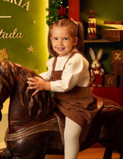 Niña sentada junto a los juguetes del decorado Juguetería Encantada