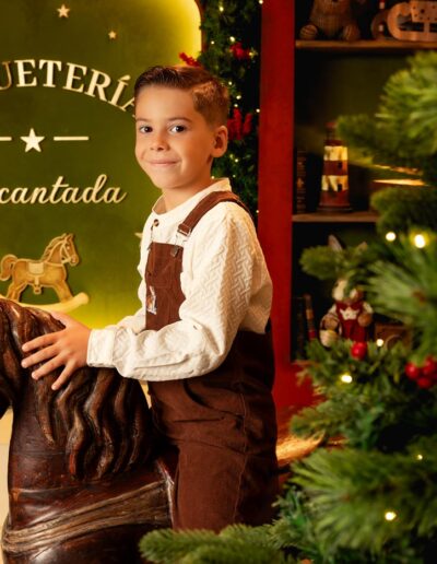 Niño posando entre regalos y juguetes en el decorado navideño