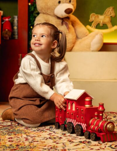 Bebé sentado entre regalos en el decorado Juguetería Encantada