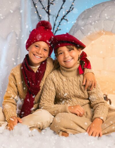 Dos hermanos con gorros rojos en el decorado El Refugio del Norte